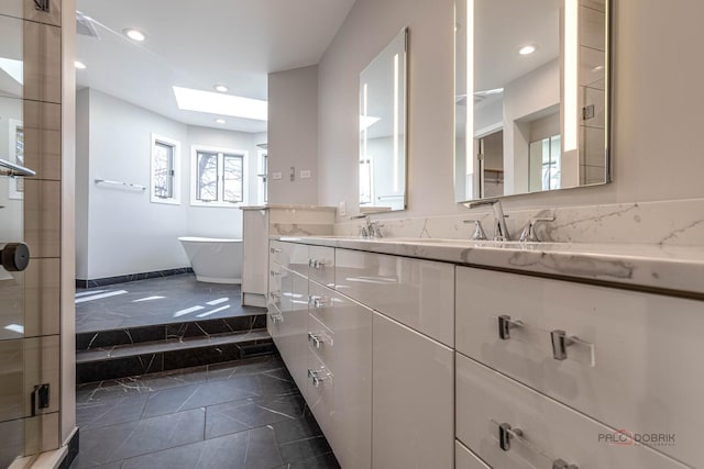 bathroom with a sink, double vanity, recessed lighting, a freestanding bath, and a skylight