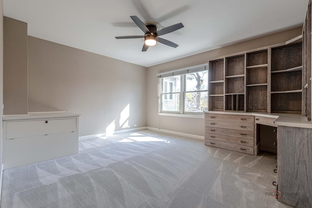 unfurnished office featuring baseboards, a ceiling fan, and light colored carpet