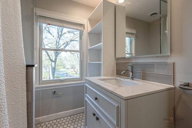 bathroom featuring baseboards, visible vents, a healthy amount of sunlight, and vanity
