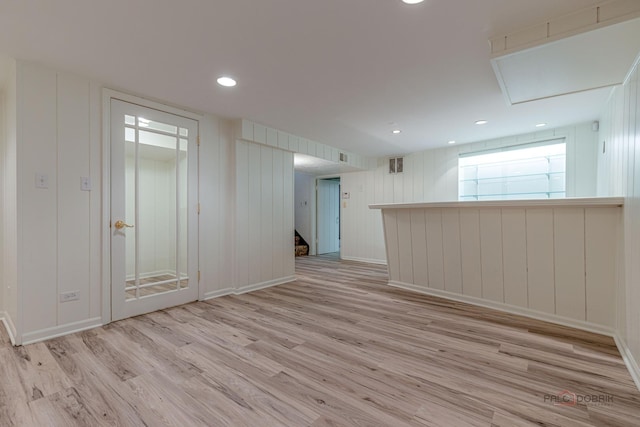 empty room featuring visible vents, stairway, light wood finished floors, and a decorative wall