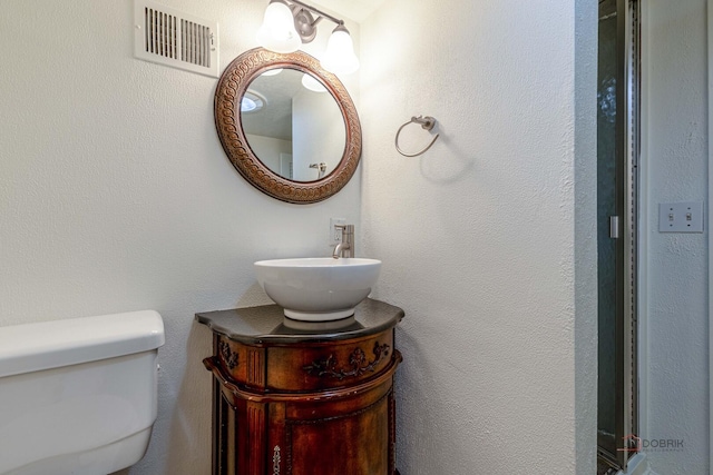 bathroom featuring visible vents, toilet, and vanity