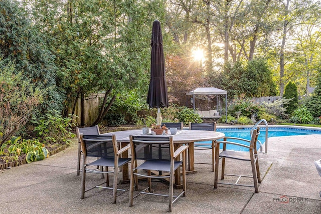view of patio with outdoor dining space, an outdoor pool, and fence