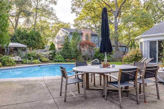 view of swimming pool featuring fence, a gazebo, a fenced in pool, outdoor dining area, and a patio area