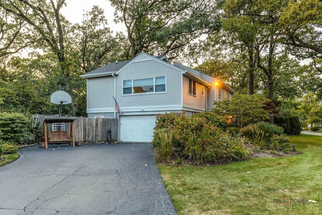 view of front of house with fence, a front yard, aphalt driveway, and an attached garage