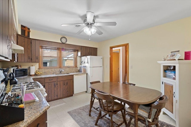 kitchen featuring white appliances, under cabinet range hood, light countertops, ceiling fan, and a sink
