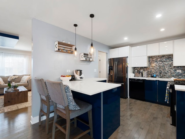 kitchen featuring a breakfast bar area, black dishwasher, dark wood-type flooring, fridge with ice dispenser, and a sink
