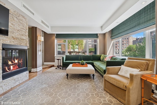 living area featuring a stone fireplace and baseboards