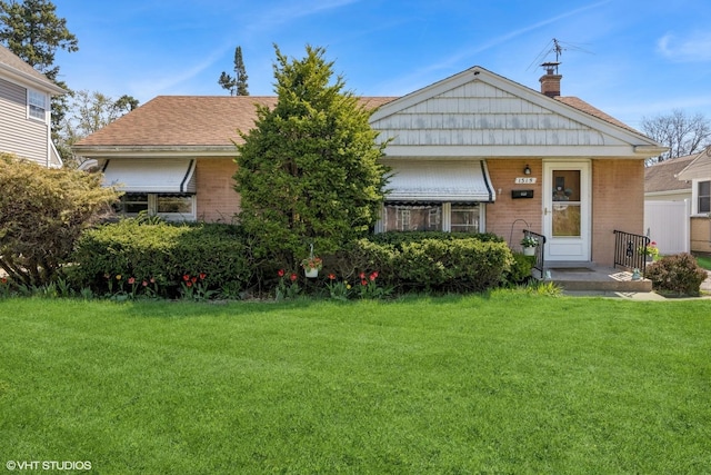 view of front of house with a chimney, a front lawn, and brick siding