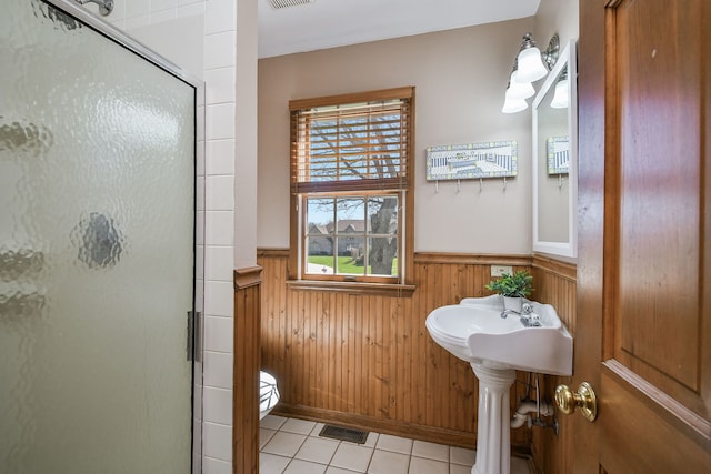 full bathroom with tile patterned floors, wainscoting, a shower stall, visible vents, and wooden walls