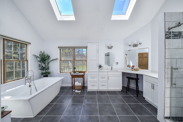 bathroom with tile patterned floors, a skylight, a stall shower, and vanity