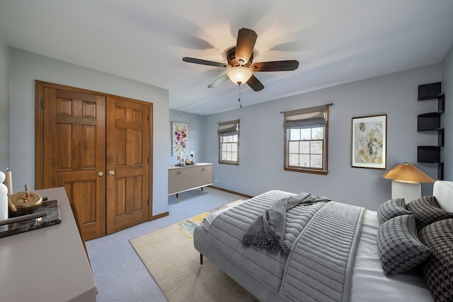 carpeted bedroom with a closet, ceiling fan, and baseboards