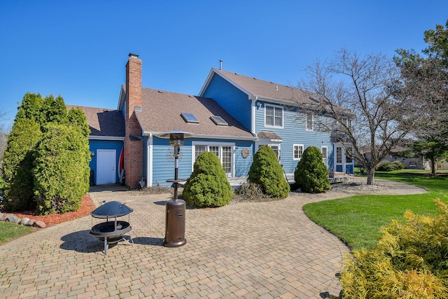 colonial inspired home with a chimney, a patio area, and a front lawn