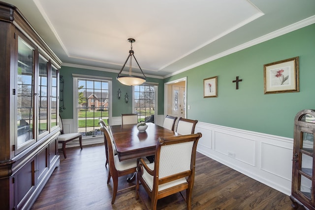 dining area featuring dark wood-style floors, wainscoting, crown molding, and a decorative wall