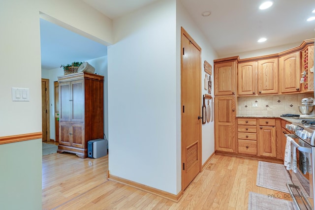 kitchen featuring light wood-type flooring, stainless steel range with gas stovetop, recessed lighting, and decorative backsplash