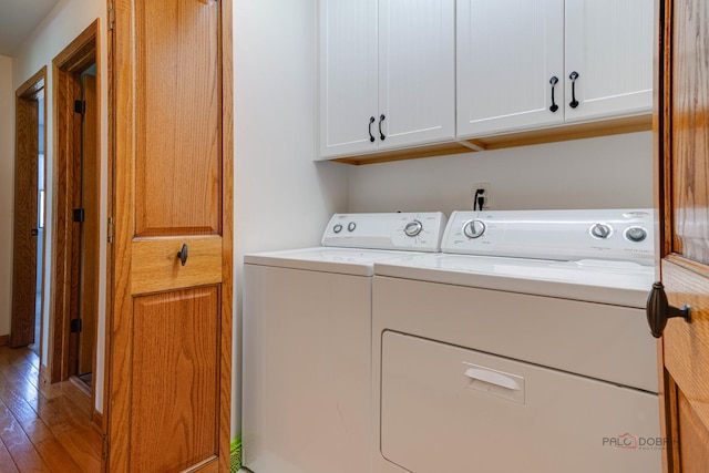 washroom featuring hardwood / wood-style floors, cabinet space, and washing machine and dryer