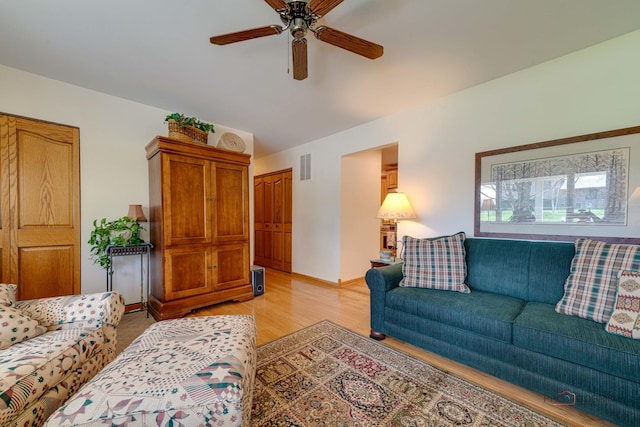 living room featuring baseboards, visible vents, ceiling fan, and light wood-type flooring