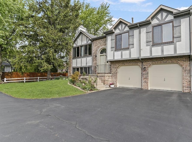 view of front of house with fence, a front yard, brick siding, an attached garage, and driveway