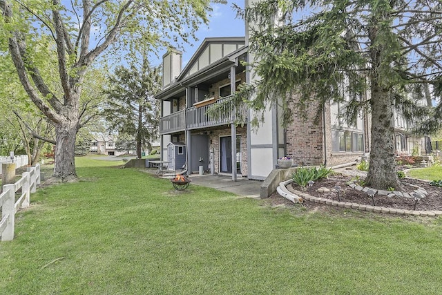 view of yard featuring a patio area, an outdoor fire pit, fence, and a balcony