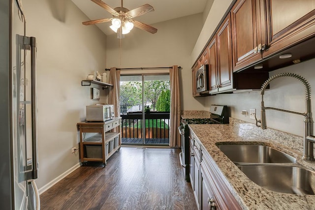 kitchen featuring a sink, brown cabinetry, stainless steel appliances, a ceiling fan, and dark wood-style floors