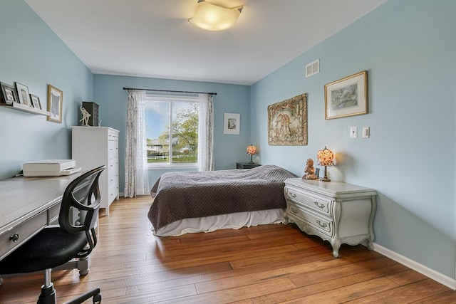 bedroom with visible vents, light wood-style flooring, and baseboards
