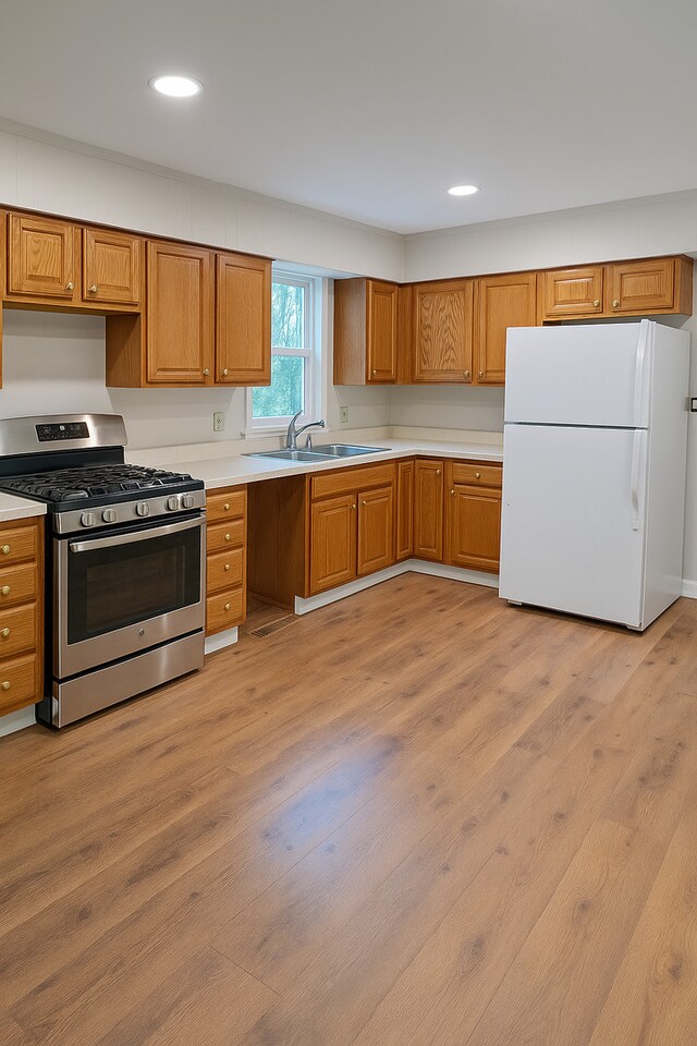 618 Princeton Rd, Depue, IL 61322 - kitchen with freestanding refrigerator, stainless steel gas range, light wood-type flooring, light countertops, and brown cabinets