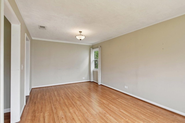 unfurnished room featuring visible vents, ornamental molding, baseboards, and light wood-type flooring