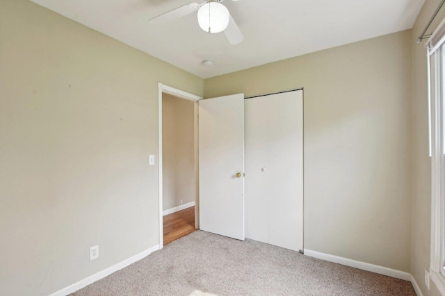 unfurnished bedroom featuring light colored carpet, a ceiling fan, baseboards, and a closet