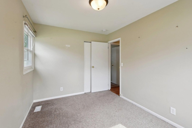 unfurnished bedroom featuring baseboards, carpet flooring, visible vents, and a closet