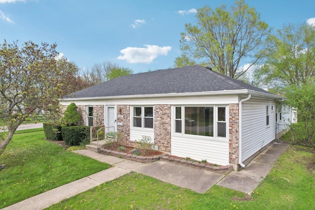 bungalow with brick siding, a shingled roof, and a front lawn
