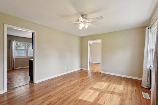 spare room featuring a ceiling fan, baseboards, visible vents, and light wood-type flooring