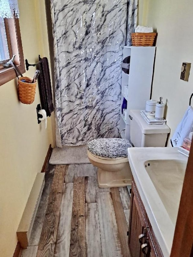 full bath with curtained shower, wood finished floors, toilet, and vanity