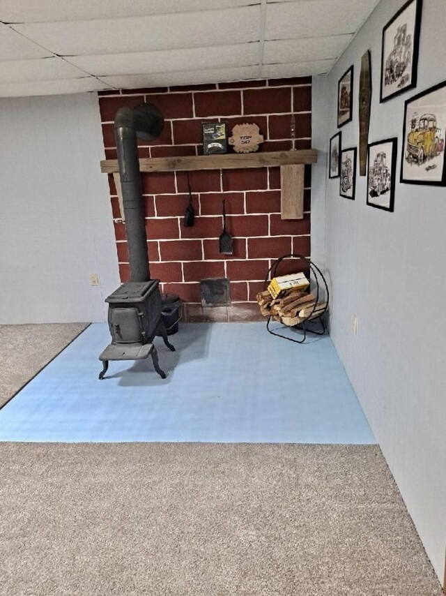 details with a wood stove, carpet, and a paneled ceiling