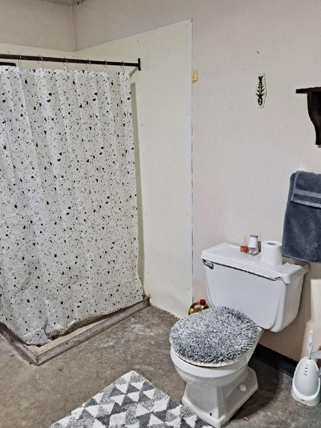 bathroom featuring toilet and curtained shower