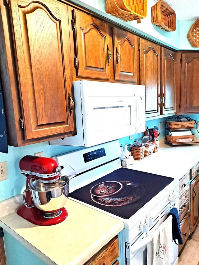 kitchen with brown cabinetry, white appliances, and light countertops