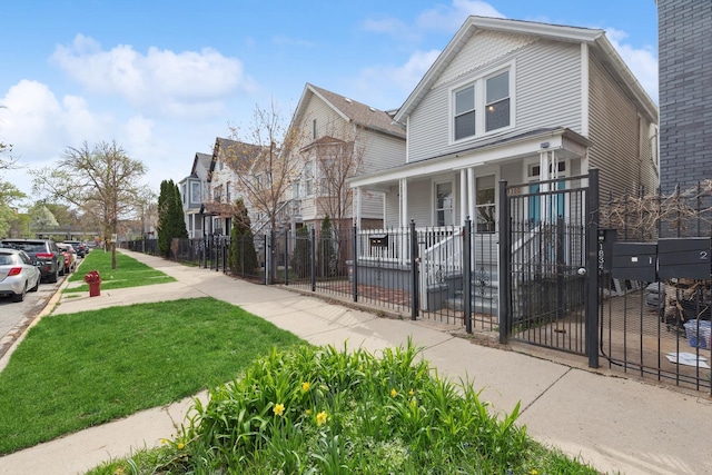 view of front of property featuring a residential view, a fenced front yard, a porch, and a front lawn