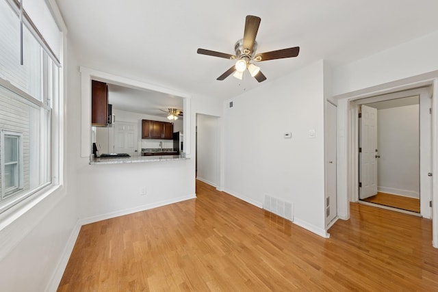 unfurnished living room featuring visible vents, ceiling fan, light wood-style flooring, and a wealth of natural light