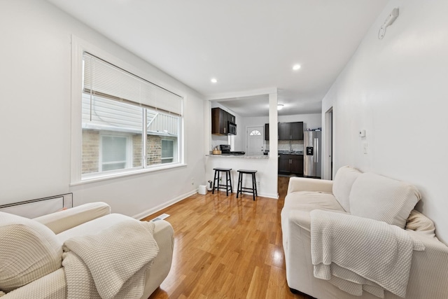 living room featuring light wood-style floors, baseboards, and recessed lighting