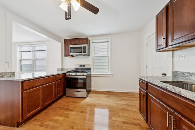 kitchen with stainless steel appliances, ceiling fan, a wealth of natural light, and light wood-type flooring