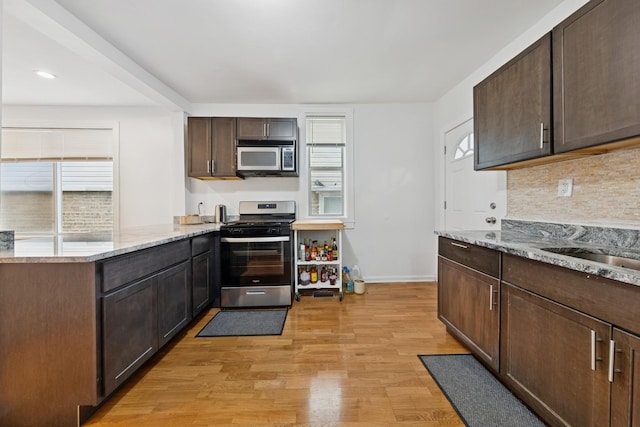 kitchen featuring light wood finished floors, a healthy amount of sunlight, dark brown cabinets, and stainless steel appliances