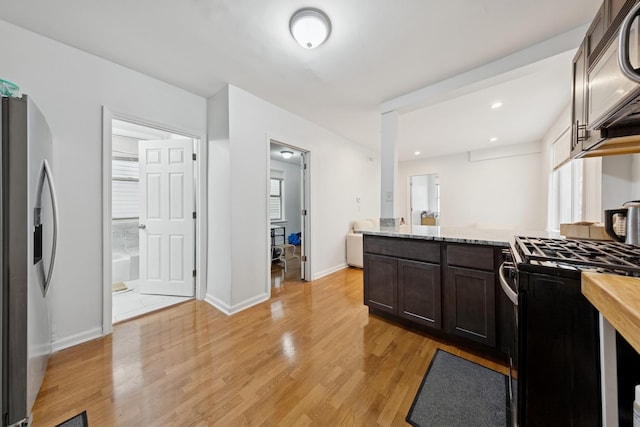 kitchen with dark brown cabinetry, baseboards, stainless steel fridge with ice dispenser, light wood-style flooring, and gas stove