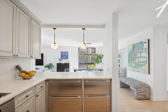 kitchen featuring decorative backsplash, pendant lighting, a peninsula, light countertops, and light wood finished floors