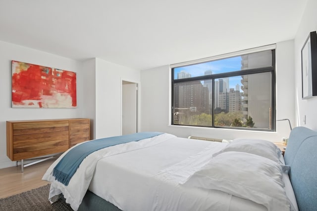 bedroom featuring a city view and wood finished floors