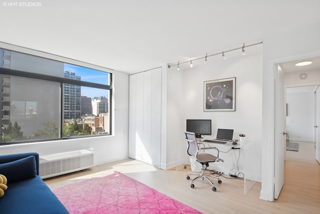 home office with track lighting, a city view, and wood finished floors