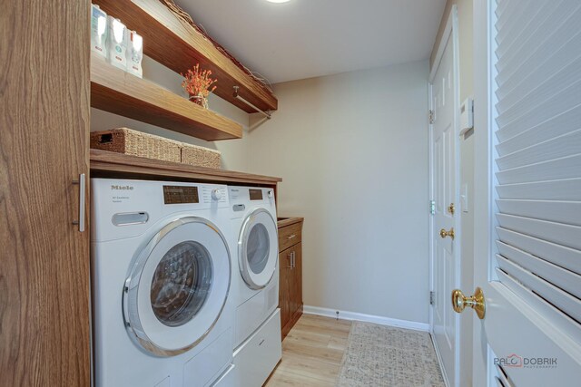 clothes washing area featuring light wood-type flooring, washer and clothes dryer, cabinet space, and baseboards