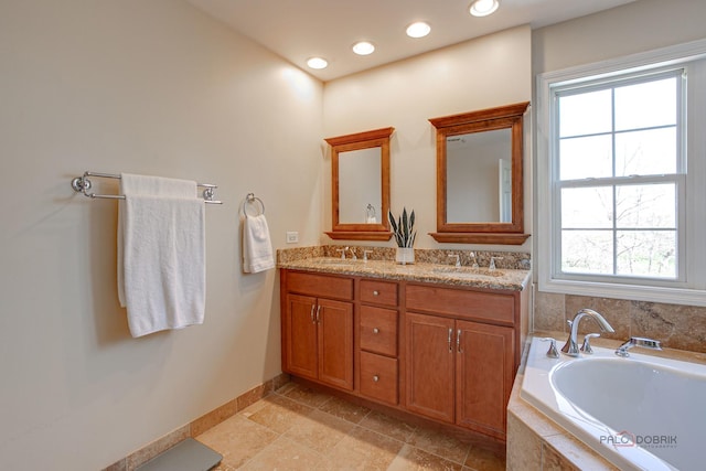 bathroom featuring double vanity, a garden tub, baseboards, and a sink