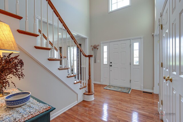 foyer featuring a high ceiling, light wood-style floors, and plenty of natural light
