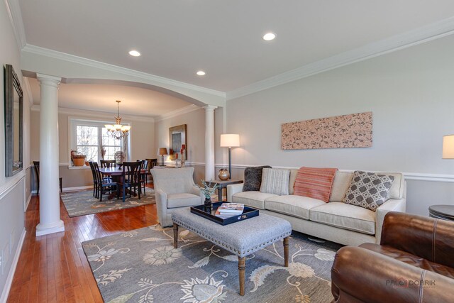 living area with baseboards, ornamental molding, wood-type flooring, and decorative columns