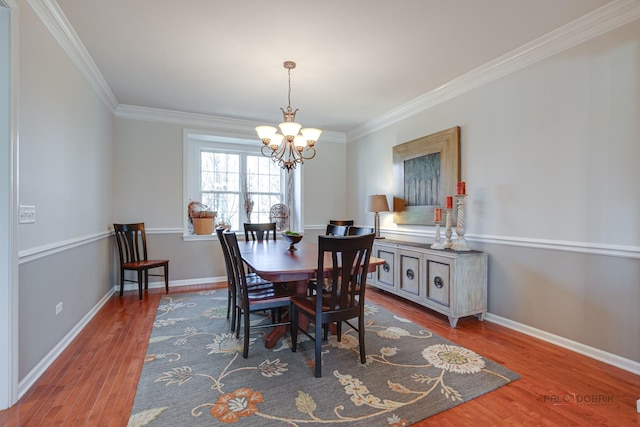 dining room featuring an inviting chandelier, wood finished floors, ornamental molding, and baseboards
