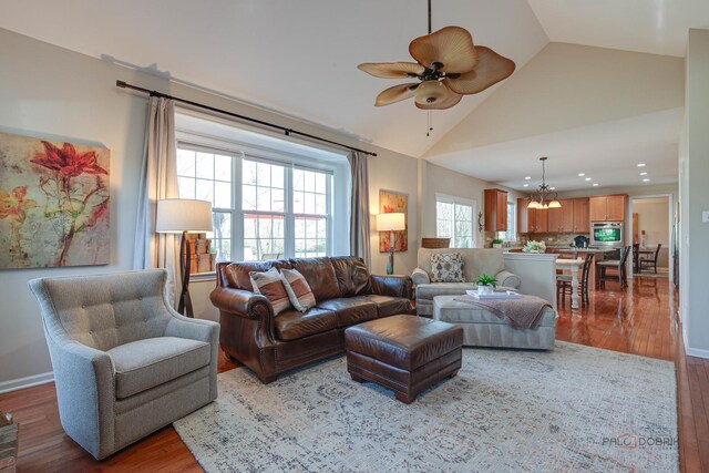 living room with wood finished floors, recessed lighting, high vaulted ceiling, and ceiling fan with notable chandelier