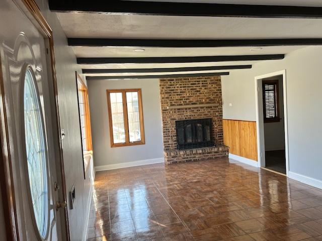 330 Oakwood St, Park Forest, IL 60466 - unfurnished living room featuring beamed ceiling, a fireplace, a wainscoted wall, wood walls, and baseboards